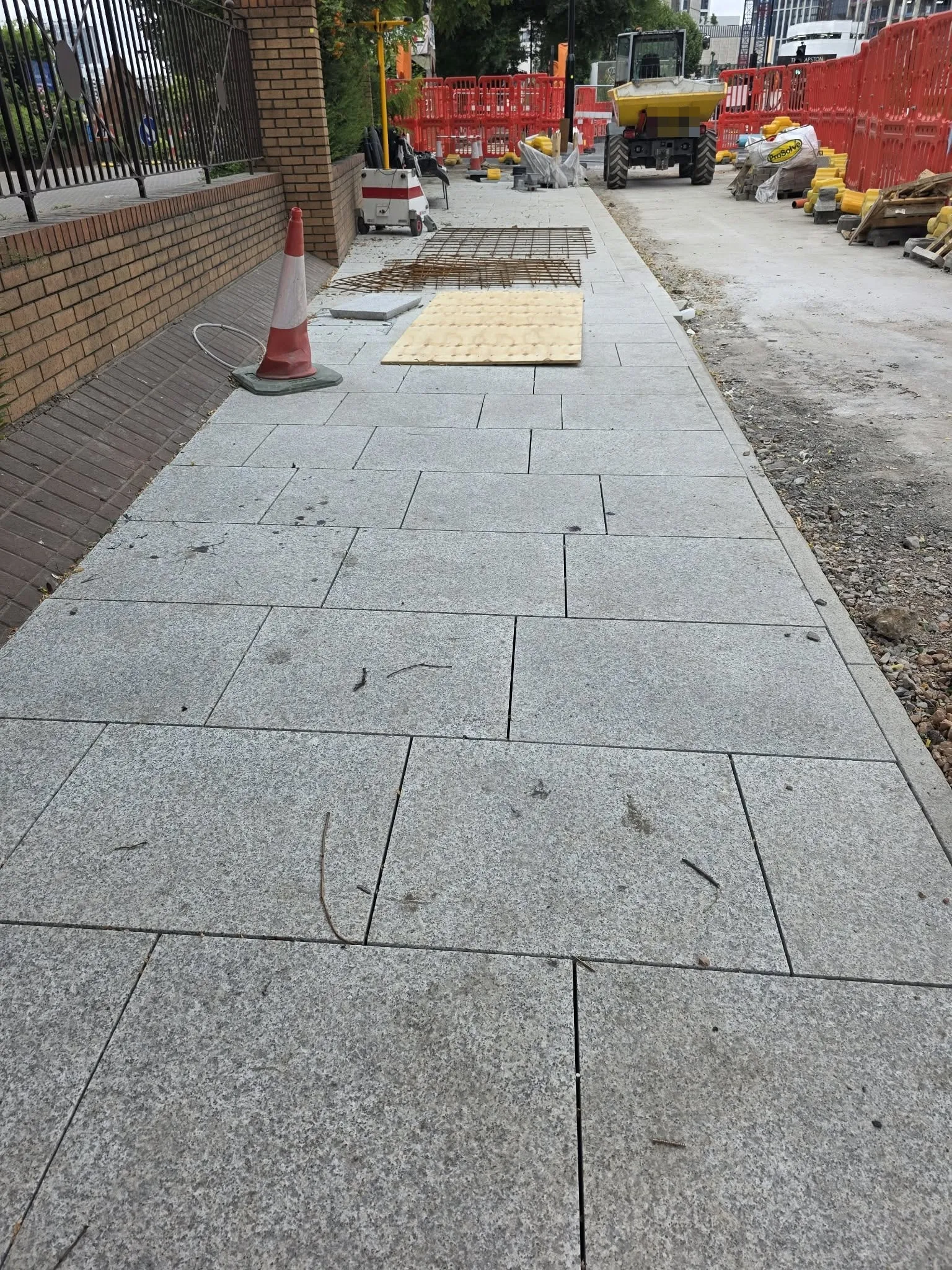 Light grey granite slabs laid along a pavement on a working site